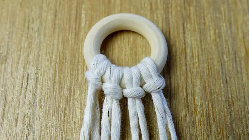 Fäden mit dem Ankerknoten am Ring befestigen